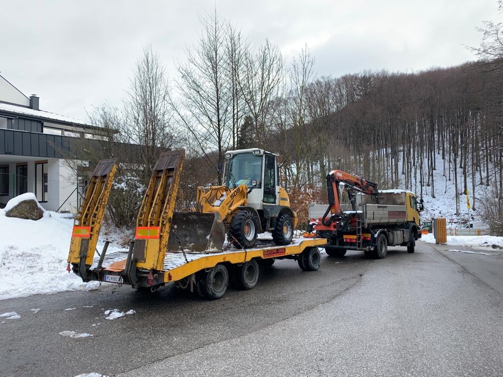 Lkw-Gespann von Transporte Rengshausen: Pritschen-Lkw mit Ladekran und Tieflader-Anhänger, auf den ein Radlader verladen wird